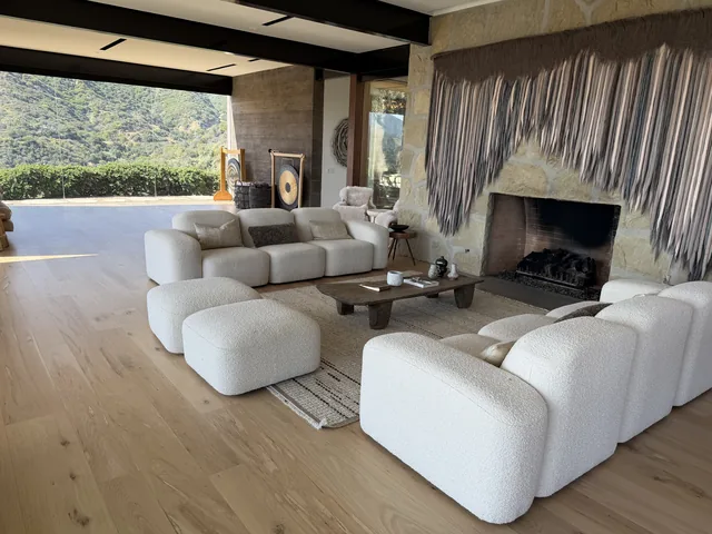 Great room with stone fireplace, woven wall hanging and gong, opening onto the hills