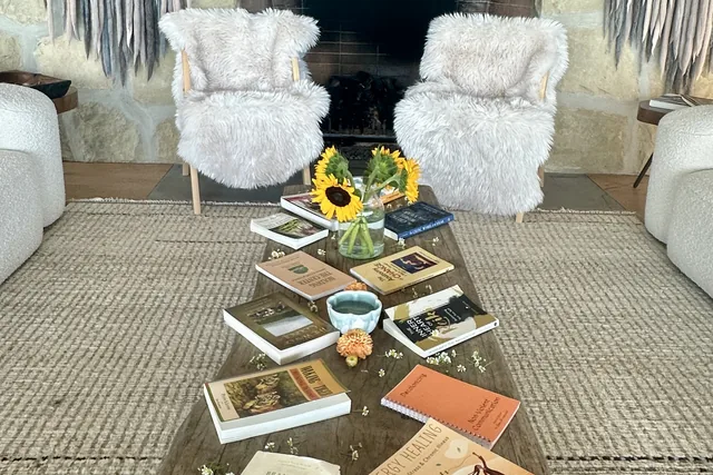 Books laid out on a wooden table by the fireplace