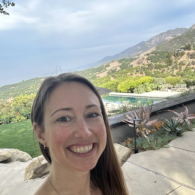 ElizaBeth outdoors at Casa Sangha, mountains and the pool behind her