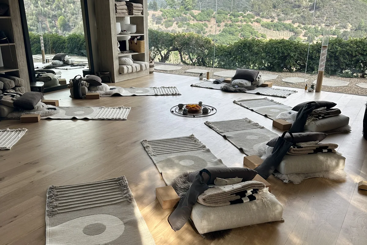 The practice space set up with mats, cushions and blankets, mountains through the window