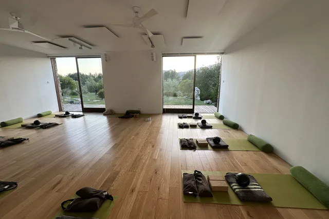 A practice room in Mallorca with mats and bolsters laid out, doors open to the garden and mountains