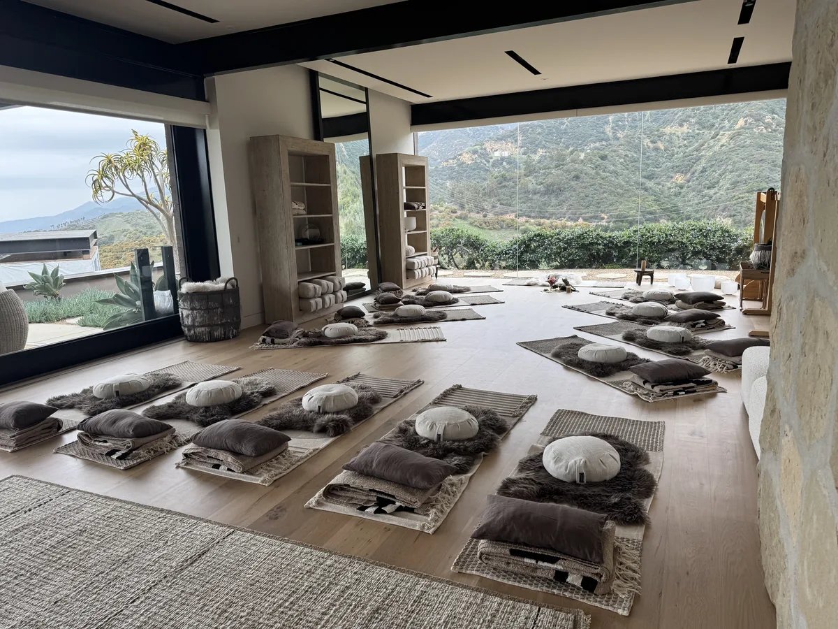 Practice space set with mats, sheepskins and cushions in a circle, glass walls open to the canyon
